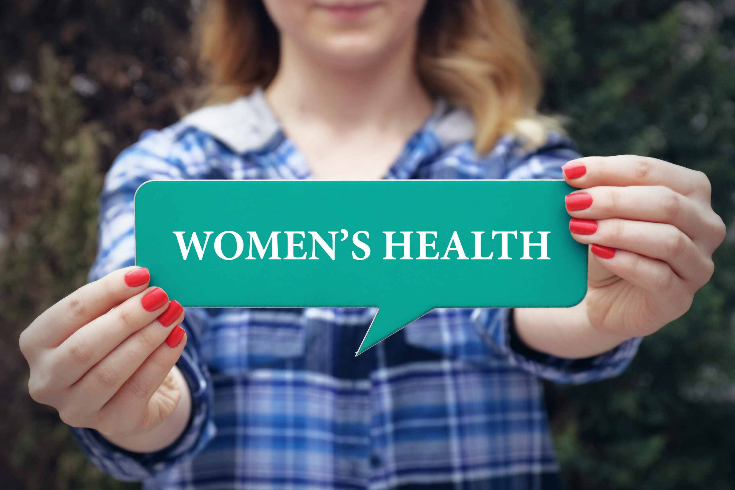 Woman holding up a green sign that says woman's health